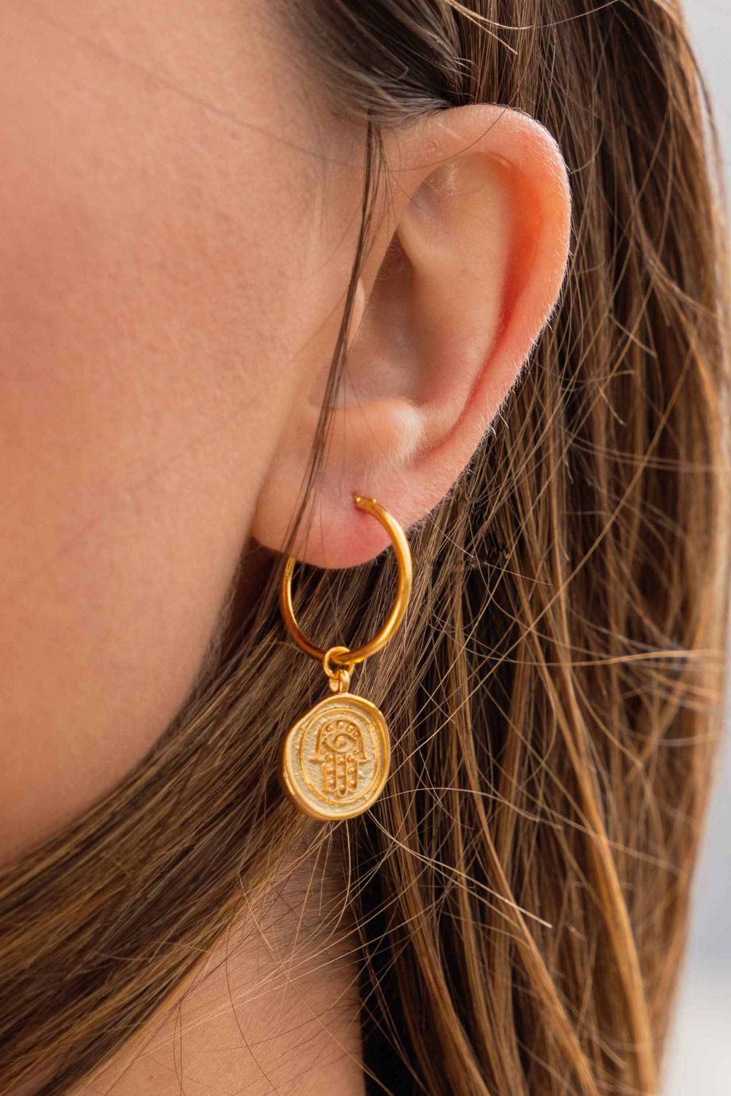 gold-hoops-hamsa-hand-statement-earrings-on-body-close-up
